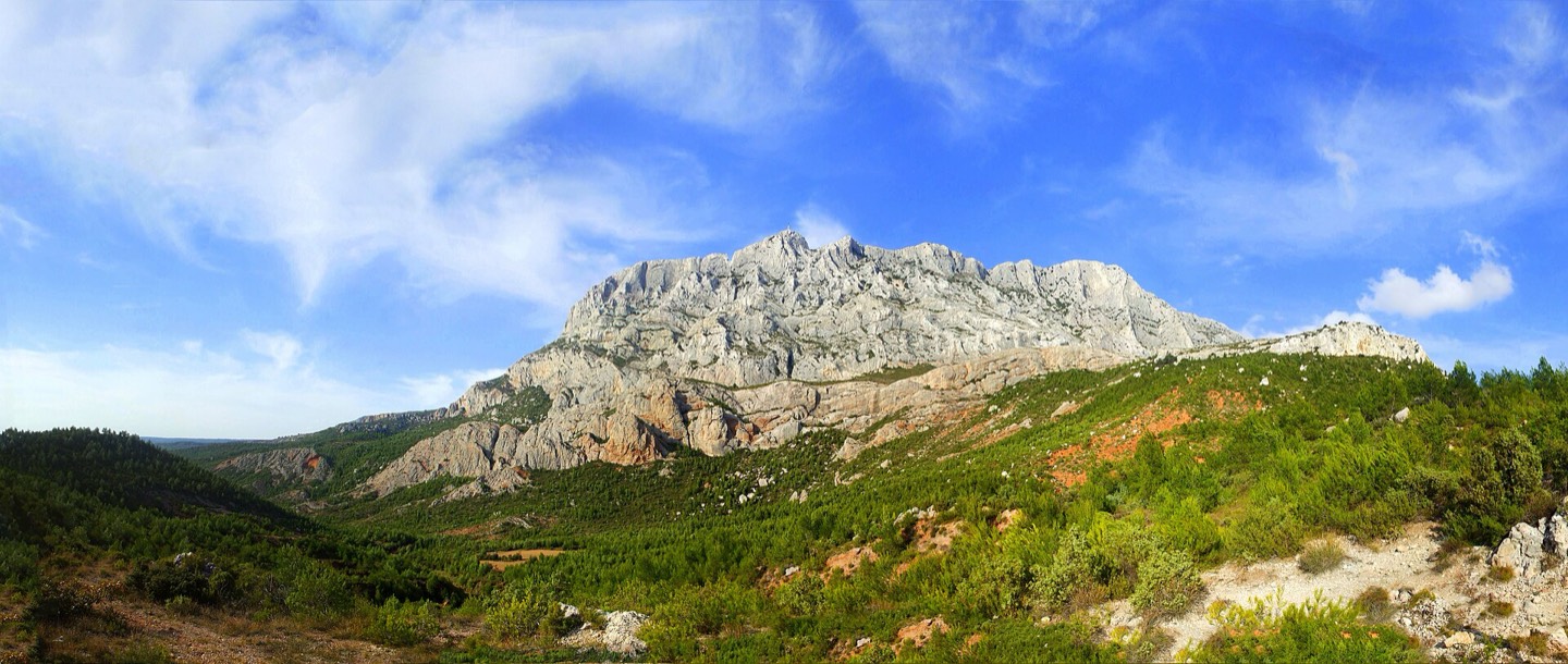 Wide view of Montagne Sainte-Victoire rising behind dry Provençal fields.